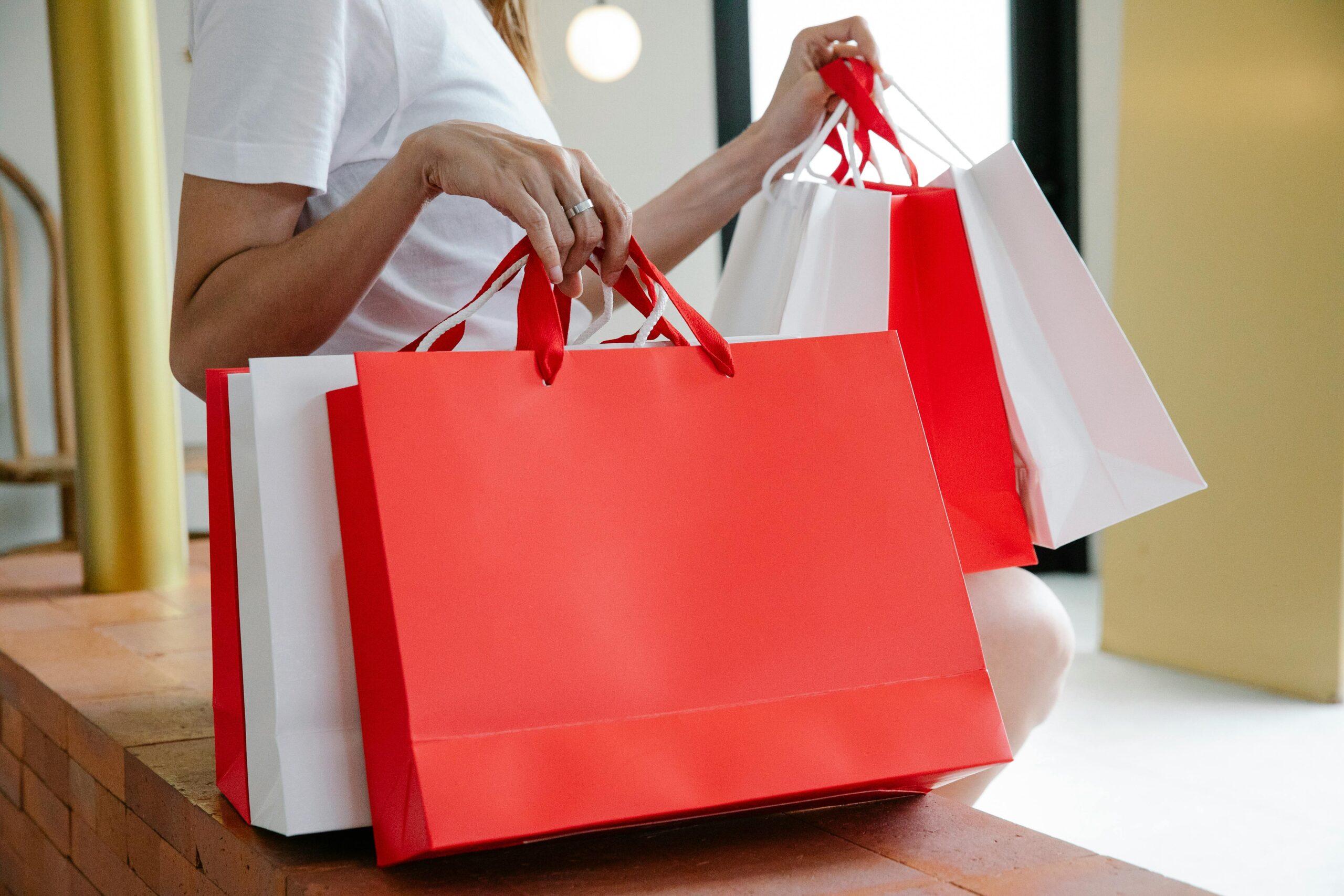 Shopper holding red and white holiday gift bags, representing customer insights into seasonal shopping patterns, gift-giving behavior, and holiday spending preferences.